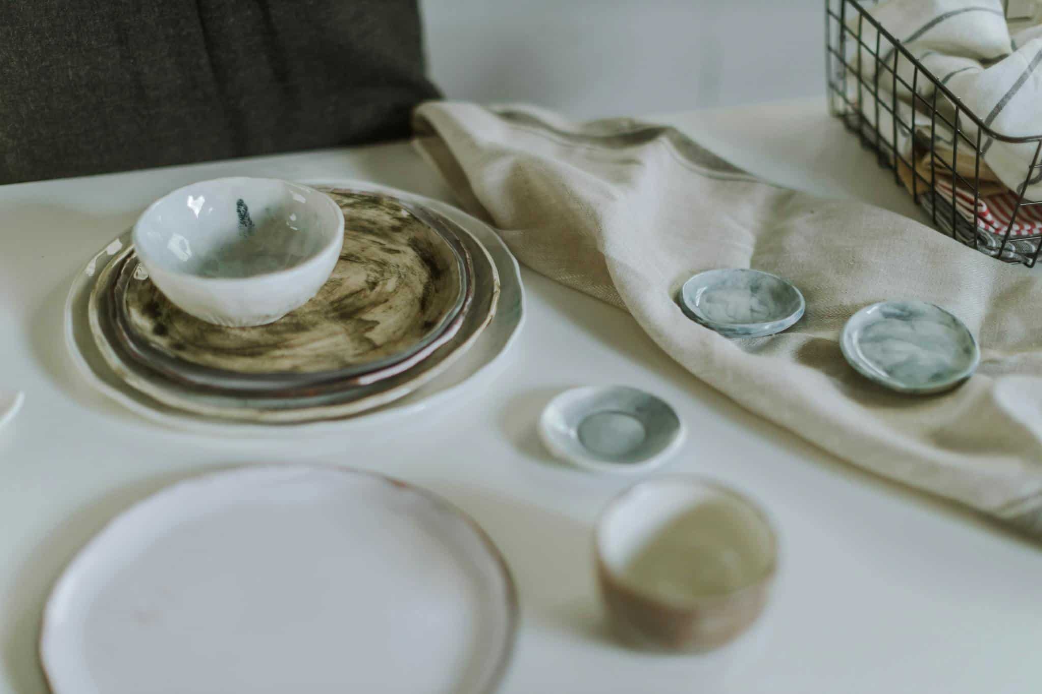 Minimalist ceramic tableware arrangement on textured fabric and white surface, highlighting elegant design.